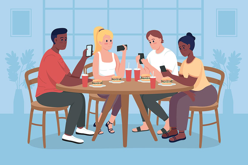 Group of people sitting around a table using their phones